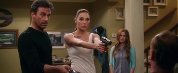 Movie still from “Keeping Up with the Joneses” (2016), directed by Greg Mottola – Gal gadot in a white shirt holding a video game controller; Medium shot, Over the shoulder angle