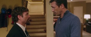 Movie still from “Keeping Up with the Joneses” (2016), directed by Greg Mottola – Two men standing next to each other in front of a staircase; Medium shot, Over the shoulder angle