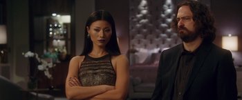 Movie still from “Keeping Up with the Joneses” (2016), directed by Greg Mottola – A woman standing in front of a man in front of a couch; Medium shot, Over the shoulder angle