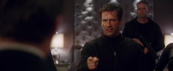 Movie still from “Keeping Up with the Joneses” (2016), directed by Greg Mottola – A man in a black jacket is pointing at the camera; Close Up shot, Over the shoulder angle