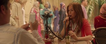 Movie still from “Keeping Up with the Joneses” (2016), directed by Greg Mottola – A woman sitting at a table with a hookah; Medium shot, Over the shoulder angle