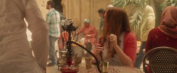 Movie still from “Keeping Up with the Joneses” (2016), directed by Greg Mottola – A woman sitting at a table with a hookah; Medium shot, Over the shoulder angle