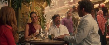Movie still from “Keeping Up with the Joneses” (2016), directed by Greg Mottola – A man and a woman sitting at a table with other people; Medium shot, Over the shoulder angle