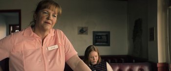 Movie still from “The Last Rampage” (2017), directed by Dwight H. Little – Two women sitting in a room with one of them holding her arm up; Close Up shot, Over the shoulder angle