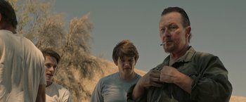 Movie still from “The Last Rampage” (2017), directed by Dwight H. Little – A man smoking a cigarette next to a young boy; Medium shot, Over the shoulder angle