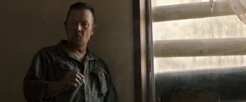Movie still from “The Last Rampage” (2017), directed by Dwight H. Little – A man standing in front of a window holding a cigarette; Close Up shot, Over the shoulder angle
