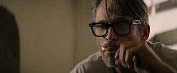 Movie still from “The Last Rampage” (2017), directed by Dwight H. Little – A person wearing glasses and smoking a cigarette; Close Up shot, Over the shoulder angle