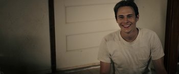 Movie still from “The Last Rampage” (2017), directed by Dwight H. Little – A young man smiling for the camera in front of a white wall; Close Up shot, Low angle