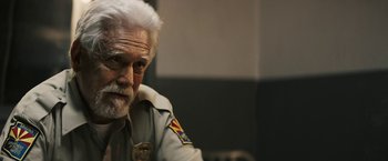 Movie still from “The Last Rampage” (2017), directed by Dwight H. Little – An older man with white hair and a police uniform; Close Up shot, Over the shoulder angle