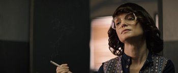 Movie still from “The Last Rampage” (2017), directed by Dwight H. Little – A woman with glasses is smoking a cigarette in front of a chalkboard; Close Up shot, Over the shoulder angle