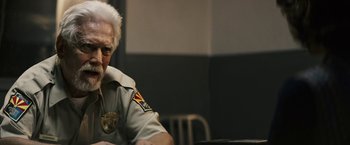 Movie still from “The Last Rampage” (2017), directed by Dwight H. Little – An older man sitting at a table in a jail cell; Close Up shot, Over the shoulder angle
