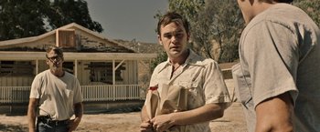 Movie still from “The Last Rampage” (2017), directed by Dwight H. Little – A man standing in front of a house holding some food; Medium shot, Low angle
