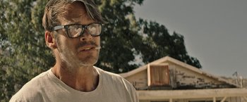 Movie still from “The Last Rampage” (2017), directed by Dwight H. Little – A person wearing glasses smoking a cigarette; Close Up shot, Low angle