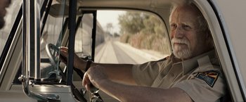 Movie still from “The Last Rampage” (2017), directed by Dwight H. Little – An older man driving a car on a road; Close Up shot, Low angle