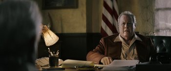 Movie still from “The Last Rampage” (2017), directed by Dwight H. Little – An older man sitting at a table with papers and a lamp; Medium shot, Over the shoulder angle