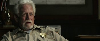 Movie still from “The Last Rampage” (2017), directed by Dwight H. Little – An older man with a white beard wearing a police uniform; Close Up shot, Low angle