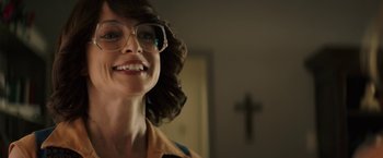 Movie still from “The Last Rampage” (2017), directed by Dwight H. Little – A person wearing glasses with a cross in the background; Close Up shot, Over the shoulder angle