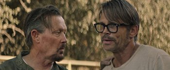Movie still from “The Last Rampage” (2017), directed by Dwight H. Little – Two men standing next to each other in front of trees; Close Up shot, Over the shoulder angle