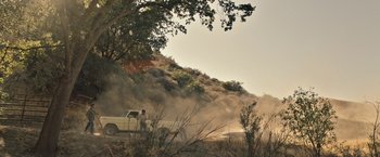 Movie still from “The Last Rampage” (2017), directed by Dwight H. Little – A truck driving down a dirt road near a tree; Extreme Wide shot, Low angle