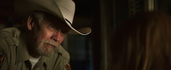 Movie still from “The Last Rampage” (2017), directed by Dwight H. Little – A man wearing a white cowboy hat and looking at the camera; Close Up shot, Over the shoulder angle