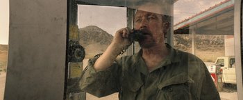 Movie still from “The Last Rampage” (2017), directed by Dwight H. Little – A man talking on a phone while standing in front of a window; Close Up shot, Over the shoulder angle