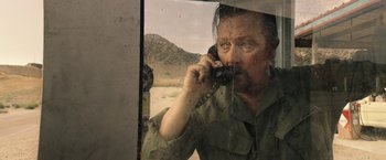 Movie still from “The Last Rampage” (2017), directed by Dwight H. Little – A man talking on a cell phone while standing in front of a window; Close Up shot, Over the shoulder angle