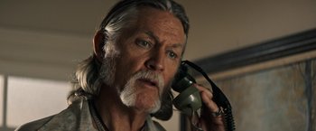 Movie still from “The Last Rampage” (2017), directed by Dwight H. Little – An older man with a long gray beard talking on a phone; Close Up shot, Low angle