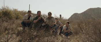 Movie still from “The Last Rampage” (2017), directed by Dwight H. Little – A group of people sitting in a field; Wide shot, Low angle
