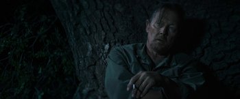 Movie still from “The Last Rampage” (2017), directed by Dwight H. Little – A man sitting in front of a tree smoking a cigarette; Close Up shot, Over the shoulder angle