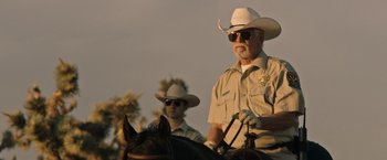 Movie still from “The Last Rampage” (2017), directed by Dwight H. Little – Two men in cowboy hats and sunglasses on a horse; Medium shot, Low angle
