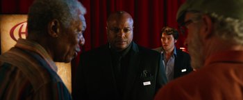 Movie still from “Last Vegas” (2013), directed by Jon Turteltaub – A man in a black suit is standing in front of two other men; Medium shot, Over the shoulder angle