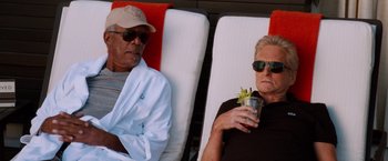 Movie still from “Last Vegas” (2013), directed by Jon Turteltaub – A man and a woman sitting on a lounge chair holding a drink; Medium shot, High angle