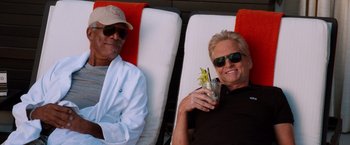 Movie still from “Last Vegas” (2013), directed by Jon Turteltaub – A man and a woman sitting on lounge chairs; Medium shot, Low angle