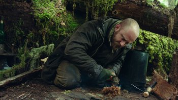 Movie still from “Leave No Trace” (2018), directed by Debra Granik – A man sitting on the ground in the woods; Medium shot, Low angle