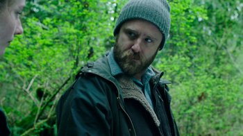 Movie still from “Leave No Trace” (2018), directed by Debra Granik – A man with a beard wearing a jacket and a hat; Close Up shot, Over the shoulder angle