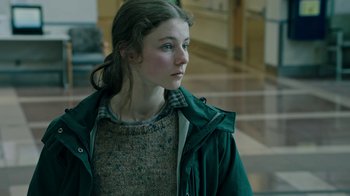 Movie still from “Leave No Trace” (2018), directed by Debra Granik – A young woman wearing a green jacket looking to her left; Close Up shot, Low angle