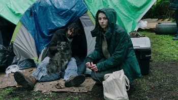 Movie still from “Leave No Trace” (2018), directed by Debra Granik – Two people and a dog sitting in front of a tent; Wide shot, Low angle
