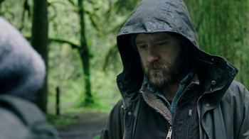Movie still from “Leave No Trace” (2018), directed by Debra Granik – A man with a beard wearing a hooded jacket; Close Up shot, Low angle