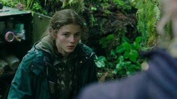 Movie still from “Leave No Trace” (2018), directed by Debra Granik – A young woman in a jacket is standing in the woods; Close Up shot, Over the shoulder angle