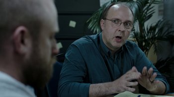 Movie still from “Leave No Trace” (2018), directed by Debra Granik – A man with glasses talking to another man in an office setting; Close Up shot, Over the shoulder angle