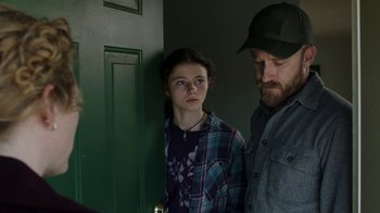 Movie still from “Leave No Trace” (2018), directed by Debra Granik – A man and a woman standing next to each other in front of a green door; Medium shot, Over the shoulder angle