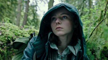 Movie still from “Leave No Trace” (2018), directed by Debra Granik – A woman with a backpack in the woods wearing a raincoat; Close Up shot, Low angle