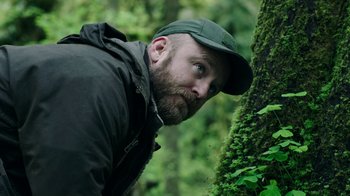 Movie still from “Leave No Trace” (2018), directed by Debra Granik – A man in a green hat leaning against a tree; Close Up shot, Low angle