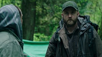 Movie still from “Leave No Trace” (2018), directed by Debra Granik – A man with a beard wearing a hat and a jacket; Medium shot, Low angle