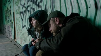 Movie still from “Leave No Trace” (2018), directed by Debra Granik – A man and a woman sitting next to each other on the ground; Medium shot, Low angle