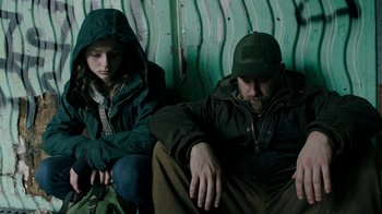Movie still from “Leave No Trace” (2018), directed by Debra Granik – A man sitting next to a woman on a bench; Medium shot, Low angle