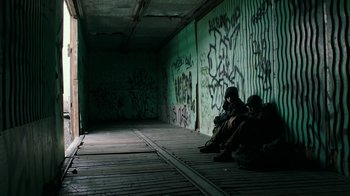 Movie still from “Leave No Trace” (2018), directed by Debra Granik – A person sitting on the ground in a tunnel; Wide shot, Low angle