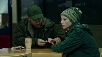 Movie still from “Leave No Trace” (2018), directed by Debra Granik – A man and a woman sitting at a wooden table; Medium shot, Over the shoulder angle