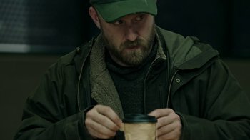 Movie still from “Leave No Trace” (2018), directed by Debra Granik – A man with a beard wearing a hat and jacket; Medium shot, High angle