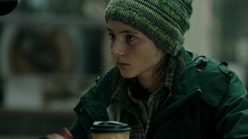 Movie still from “Leave No Trace” (2018), directed by Debra Granik – A young girl wearing a hat and holding a cup of coffee; Close Up shot, Over the shoulder angle